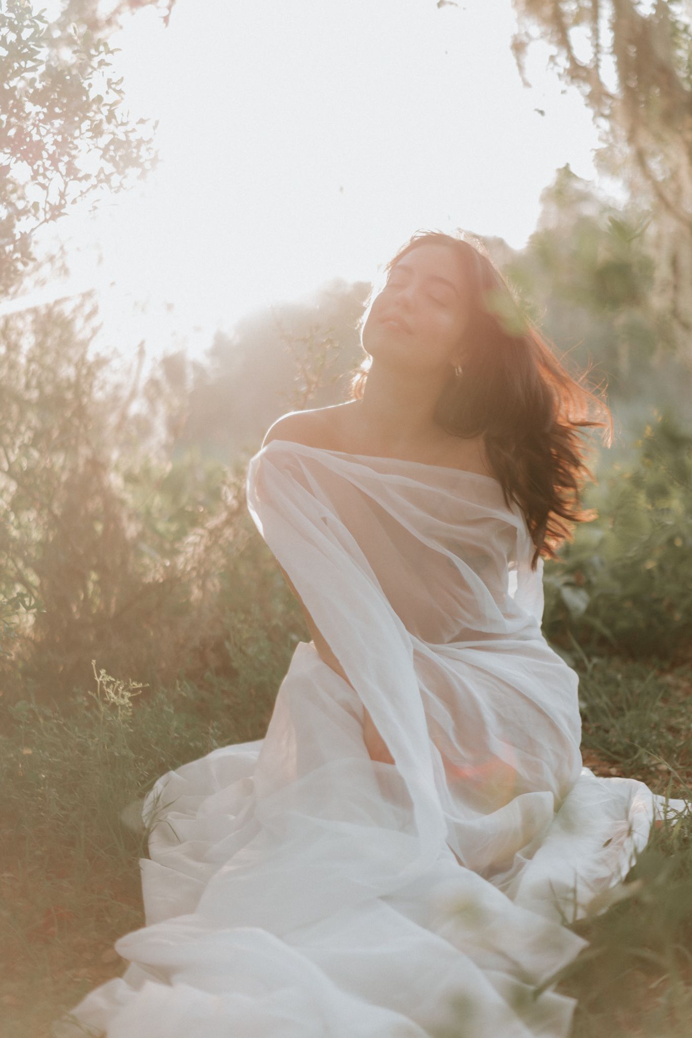 A woman draped in white silk in golden light